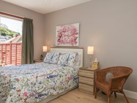 A bedroom with a bed, nightstand, lamp, and chair at 3 Heath Park in Brixham