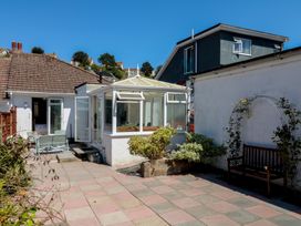 A garden with a conservatory and seating area at 3 Heath Park Brixham