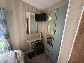 A bedroom with a bed, mirror, and television at Haggerston Castle Lakeside East 76 Berwick-upon-Tweed