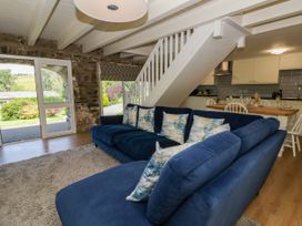 A living room with a sofa and kitchen area at The Cart House in Pontsian