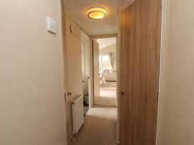 A hallway with doors and a radiator at 56 The Stables in Pwllheli