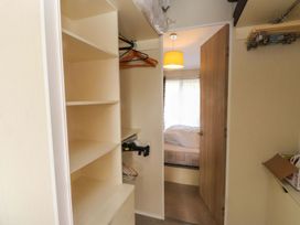 A closet with shelves and hangers in a bedroom at 56 The Stables Pwllheli