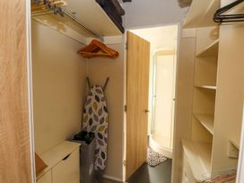 A closet with shelves and an ironing board at 56 The Stables Pwllheli