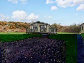 A house with a deck and grass area at 56 The Stables in Pwllheli