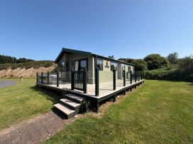 A house with a deck and stairs in an outdoor setting at The Stables Pwllheli