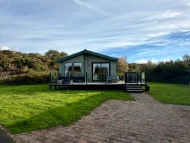 A house with a deck and glass doors in an outdoor area at The Stables in Pwllheli