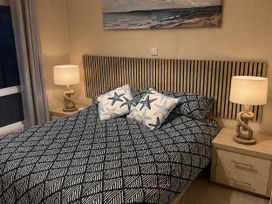 A bedroom with a bed, bedside tables, and lamps at The Stables in Pwllheli