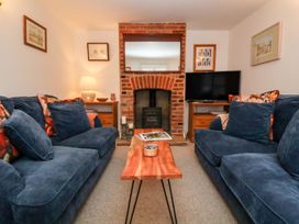 A living room with a sofa, coffee table, and fireplace at Cobblers Cottage in Southwold