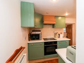 A kitchen with cabinets, microwave, stove, and toaster at Cobblers Cottage in Southwold