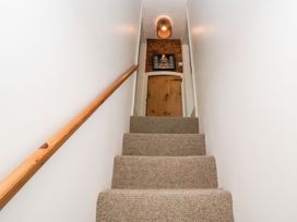 A staircase with a handrail and door at Cobblers Cottage in Southwold