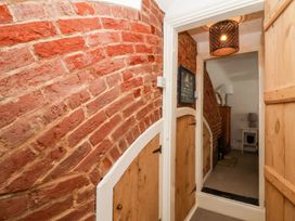 A hallway with a brick wall and wooden doors at Cobblers Cottage in Southwold
