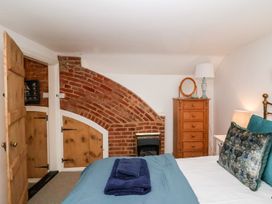 A bedroom with a bed and wardrobe at Cobblers Cottage in Southwold