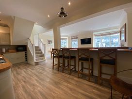 A kitchen with bar stools and staircase at Nesden House