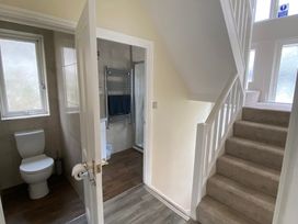 A hallway with a staircase and a bathroom door at Nesden House