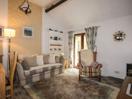 A living room with a sofa, chair and shelves at Riverside Cottage in Caernarfon