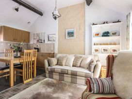 A living room with a dining area and kitchen cabinets at Riverside Cottage in Caernarfon