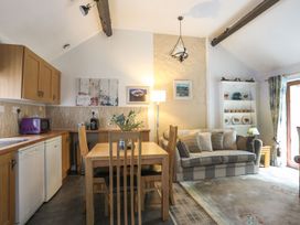 A living room with a dining table and kitchen cabinets at Riverside Cottage in Caernarfon