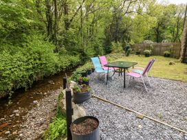 A garden area with a table and chairs beside a stream at Riverside Cottage in Caernarfon