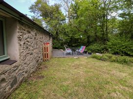 A garden with stone wall and chairs around a table at Riverside Cottage in Caernarfon
