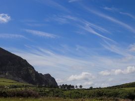 A landscape with a mountain and trees under a cloudy sky at Riverside Cottage in Caernarfon