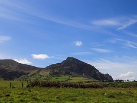 A mountain in a field under a blue sky at Riverside Cottage in Caernarfon