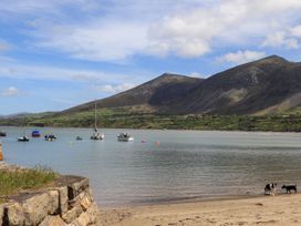 A beach with boats in the water and dogs on the sand at Riverside Cottage in Caernarfon