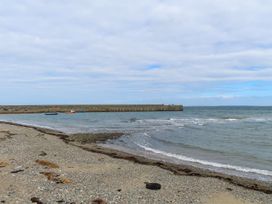 A beach with a pier and boats at Riverside Cottage in Caernarfon