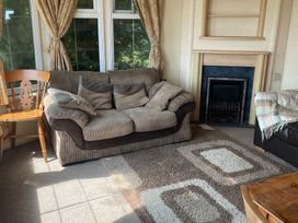 A living room with a sofa and chair near a fireplace at Windy Ridge in Penzance