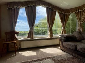 A living room with a large window and a chair at Windy Ridge in Penzance
