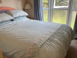 A bedroom with a bed and windows at Windy Ridge in Penzance