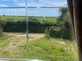 A view of a field and path seen through a window at Windy Ridge in Penzance