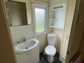 A bathroom with a sink, toilet, and mirror at Windy Ridge in Penzance