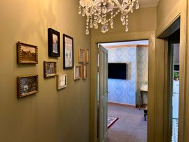 A hallway with framed pictures and a chandelier at Downton II in Alnwick