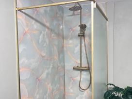 A shower with a glass door and a tiled wall at Downton II in Alnwick