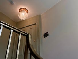 A staircase with a chandelier and a door at Downton II in Alnwick