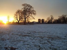 A snowy field with trees and a sunset at No 1 The Martins Walberswick