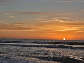 A sunset over the ocean with waves at No 1 The Martins Walberswick