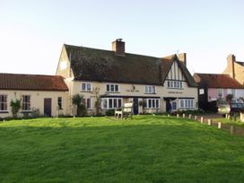 An inn with a sign and benches in front at No 1 The Martins Walberswick