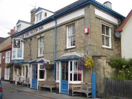 A pub exterior with benches and flowers at The Lord Nelson Inn in Walberswick