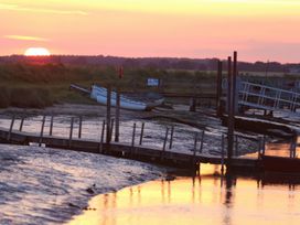 A sunset over water with a boat and jetty at No 1 The Martins Walberswick
