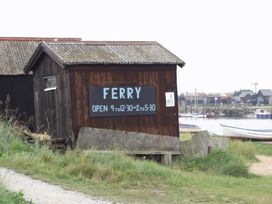 A wooden building with a ferry sign located by a river at No 1 The Martins in Walberswick