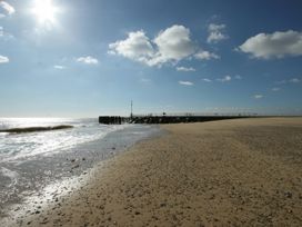 A beach with a pier and ocean at No 1 The Martins in Walberswick