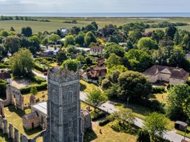 An aerial view of a church tower surrounded by houses and fields at No 1 The Martins in Walberswick