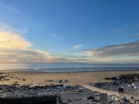 A beach with rocks and people walking at 7 Adrian Close Porthcawl
