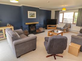 A living room with a sofa, armchair, and television at Ty Traeth in Porthcawl