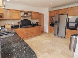 A kitchen with wooden cabinetry and appliances at Ty Traeth in Porthcawl