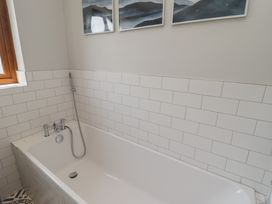 A bathroom with a bathtub and window at Ty Traeth in Porthcawl
