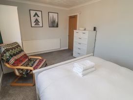 A bedroom with a bed and a chair at Ty Traeth in Porthcawl