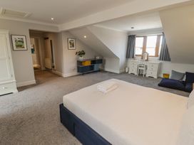 A bedroom with a bed, dresser, chair, and window at Ty Traeth in Porthcawl