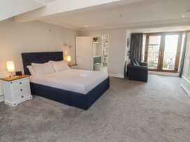 A bedroom with a bed and armchair at Ty Traeth in Porthcawl